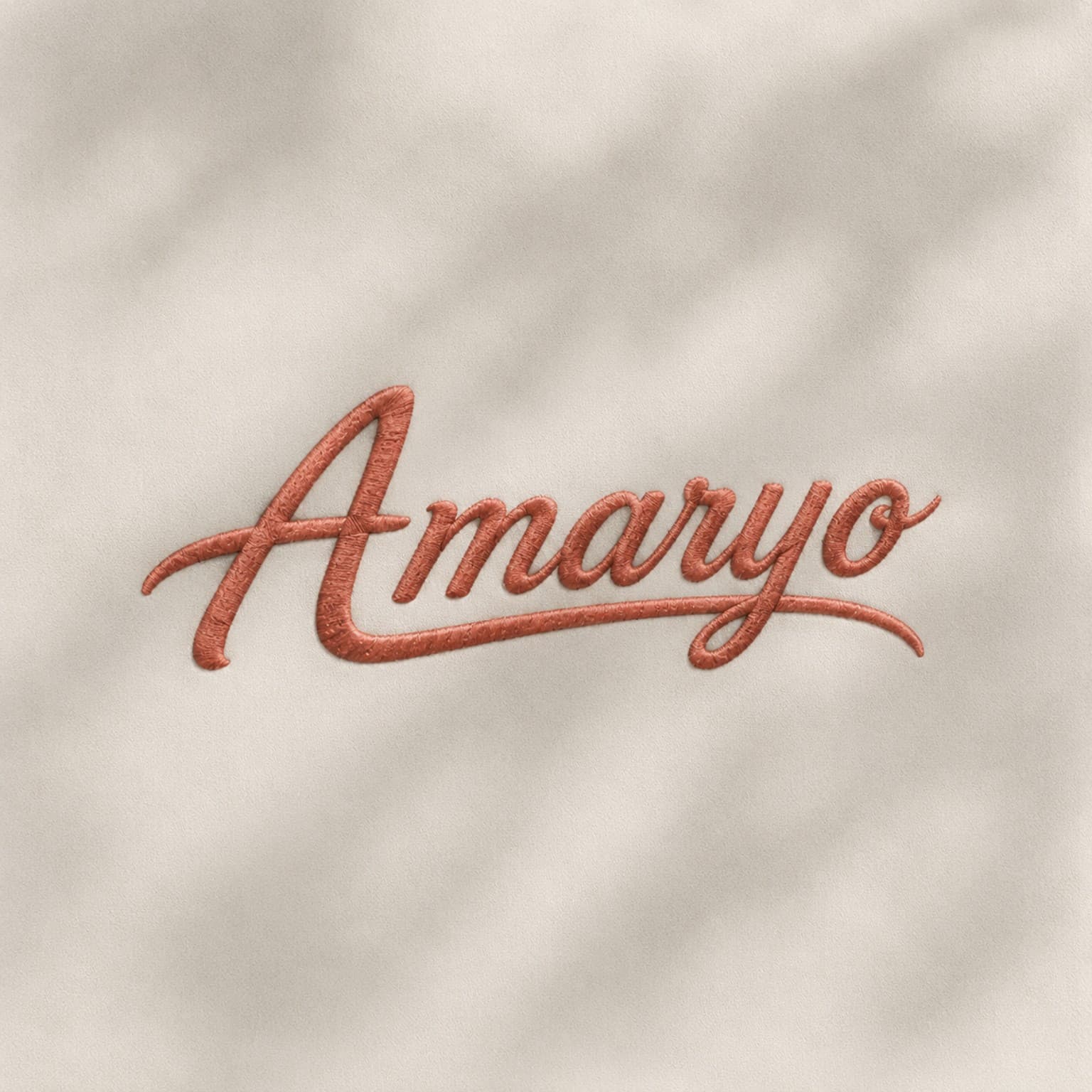 Signature AMARYO brodée en corail sur textile clair